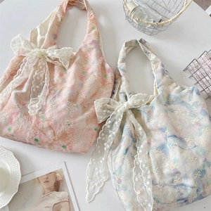 Detalle de bolsos de mano con lazos de encaje y bordado de mariposa en azul y rosa