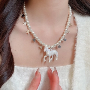 Détail du collier de perles avec étoile argentée et pendentif licorne irisée sur modèle