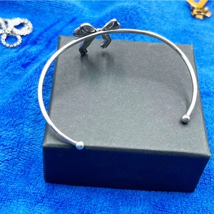 Détail macro d'un bracelet jonc argenté avec nœud papillon sur un écrin à bijoux