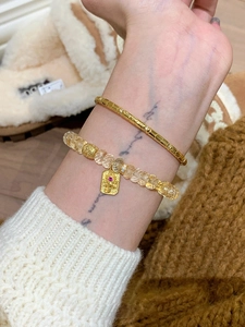 Vue détaillée du jonc doré et du bracelet en perles jaunes avec un pendentif d'éléphant