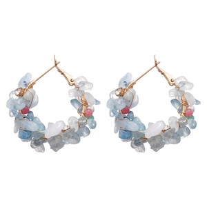 Handmade hoop earrings with blue natural stones and gold wire wrap on white background