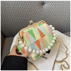 Close-up of retro shell bag featuring vibrant geometric patterns and elegant pearl handle