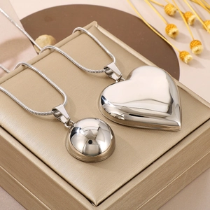 Macro view of polished silver hollow heart and sphere pendants on snake chains