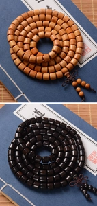 Macro shot of 8mm barrel-shaped sandalwood prayer beads on a classic blue vintage book