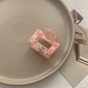Dettaglio di una pinza per capelli rettangolare rosa marmorizzata in un piatto