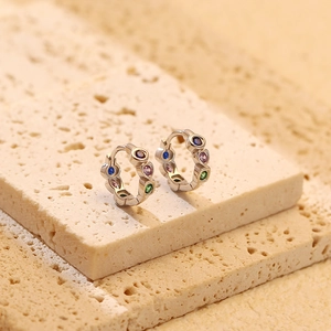 Macro view of colorful zircon heart earrings on beige stone showing silver craftsmanship