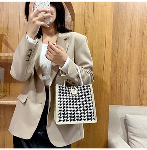 Close-up of houndstooth tote bag featuring woven rope handles and a wooden button closure