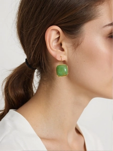 Détail de la boucle d'oreille rétro en or avec pierre de jade verte sur un modèle