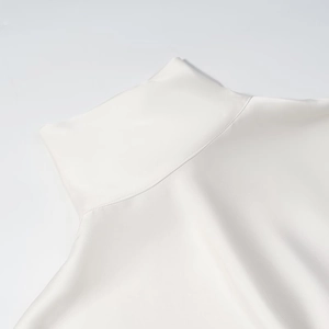 Gros plan détaillé du col montant sur la robe en satin blanc perle à texture soyeuse