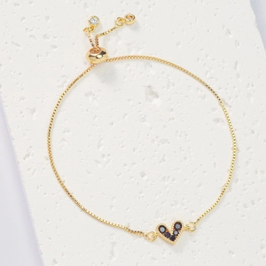 Detail of adjustable gold bracelet featuring a black zircon heart charm and slider clasp