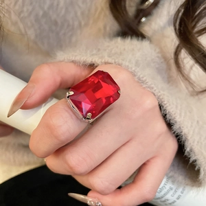 Close-up of a square red gemstone ring featuring a silver four-prong setting worn on hand