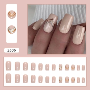 Solid nude pink square press-on nails with gold V-shape stripes and rhinestones