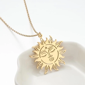 Detailed view of a golden vintage sun face pendant necklace in a white dish