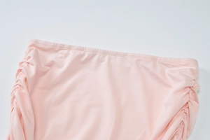 Detail view of pink elastic fabric featuring side ruched design and fine waist stitching