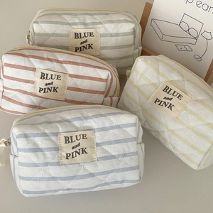 Dettaglio di quattro trousse trapuntate a righe con etichetta BLUE and PINK colorate