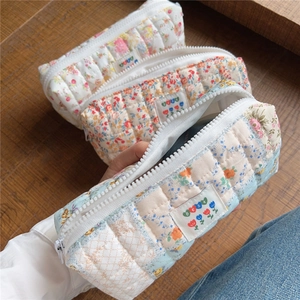 Detailed view of hand-held quilted cotton floral pouch with soft texture and zip closure