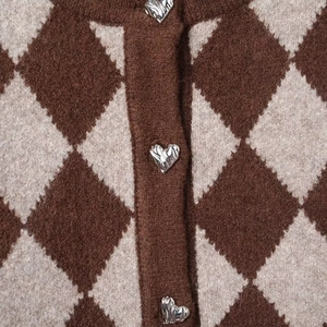 Detail of argyle knit cardigan featuring brown diamond patterns and heart-shaped metal buttons