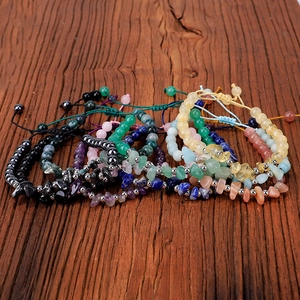 Handmade woven bracelet with natural amethyst and citrine stones on dark wood background