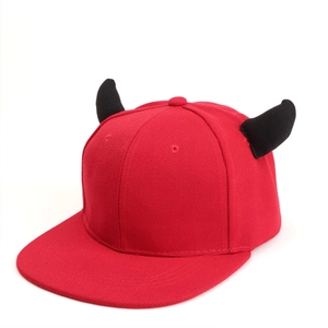 Detail of red snapback hat featuring black plush devil horns and twill fabric texture