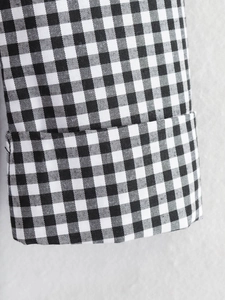 Detailed view of black and white gingham pattern fabric and stitched cuff sleeve texture