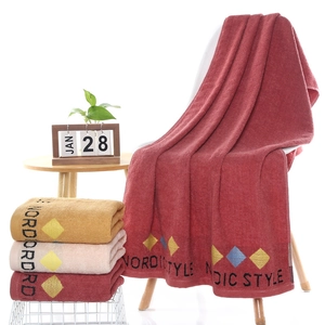 Thick cotton Nordic style bath towel in wine red color draped over a white chair