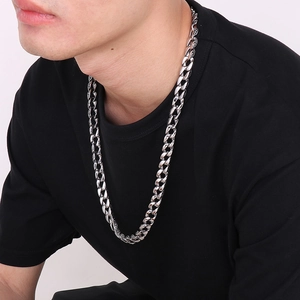 Detail of silver men's Cuban chain with intricate floral patterns worn by a male model