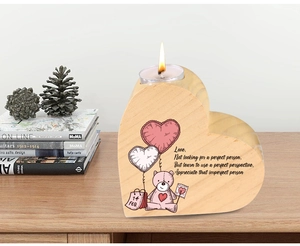 Close-up of wooden heart candle holder with 14 Feb print and lit tealight on a table