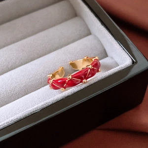 Detailed shot of red enamel ring with gold edges inside a gray velvet jewelry box