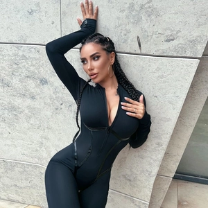 Detail of black slim fit bodysuit featuring sporty zipper and outdoor marble wall background