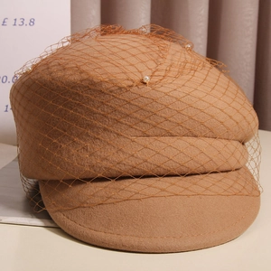 Detail of camel wool beret featuring fine mesh veil and delicate white pearl accents