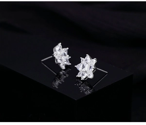 Macro detail showing sparkling flower-shaped stud earrings with premium zircon inlay