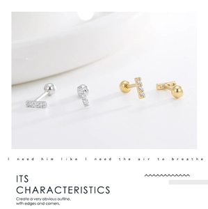 Detailed view of silver and gold bar earrings with five small inlaid zircons and screw backs