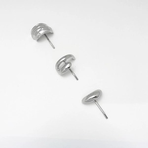 Close-up of polished silver geometric stud earrings in wavy spiral and curved shapes