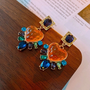 Macro shot of vintage baroque earrings with heart-shaped orange gems and colorful crystals