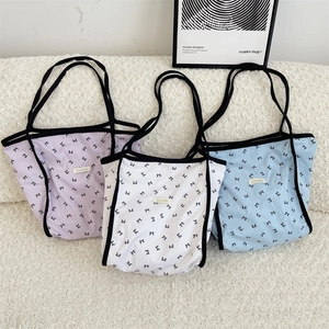 Dettaglio di tre borse tote in tessuto con motivi a fiocco in viola, bianco e blu
