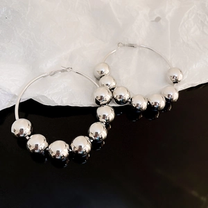 Boucles d'oreilles créoles argentées avec de grosses perles métalliques et fini poli