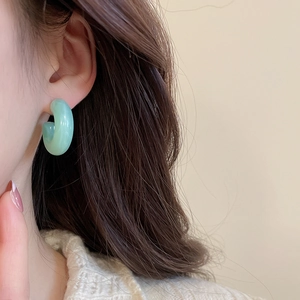 Close-up of mint green marble resin C-hoop earrings worn by a model in a casual style