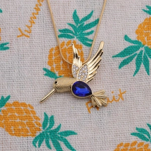 Gros plan du pendentif colibri avec pierre poire bleue et cristaux blancs brillants