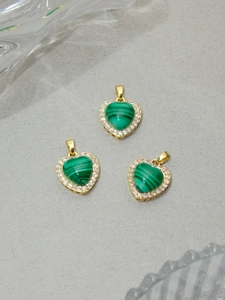 Macro detail of three green malachite heart pendants with gold halo and white crystals