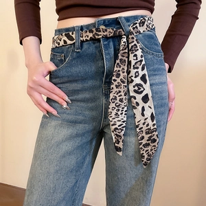 Detail of high-waist blue jeans styled with a leopard print chiffon scarf belt