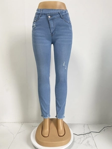 Detail der hohen Jeans mit asymmetrischer Knopfleiste und Destroyed-Effekt am Knie