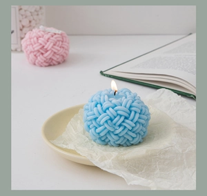 Close-up of a lit blue yarn ball shaped scented candle on a decorative plate