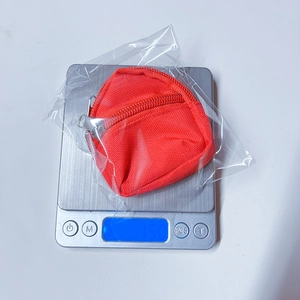 Mini red backpack keychain wallet shown on a digital scale weighing 15.0 grams