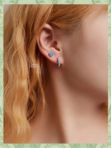 Close-up of 925 silver turquoise flower stud and gold hoop earring set on female ear