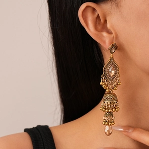Detailed close-up of model wearing vintage bronze jhumka earrings with tassels