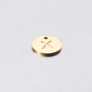 Macro view of gold stainless steel round charm with engraved letter X for DIY jewelry