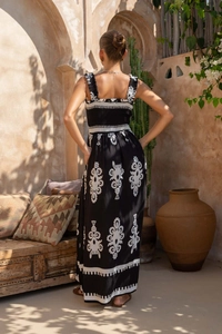 Detail view of Bohemian backless maxi dress with white embroidery on black fabric