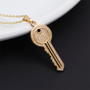 Macro shot of gold-plated key pendant necklace with crystals on white plate