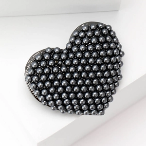 Detail of a heart brooch featuring black micro-pave beads on white geometric stands