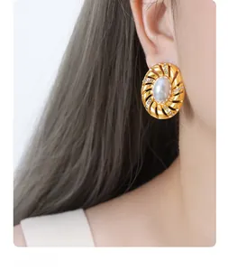 Gros plan de boucles d'oreilles spirales dorées avec perles blanches et cristaux